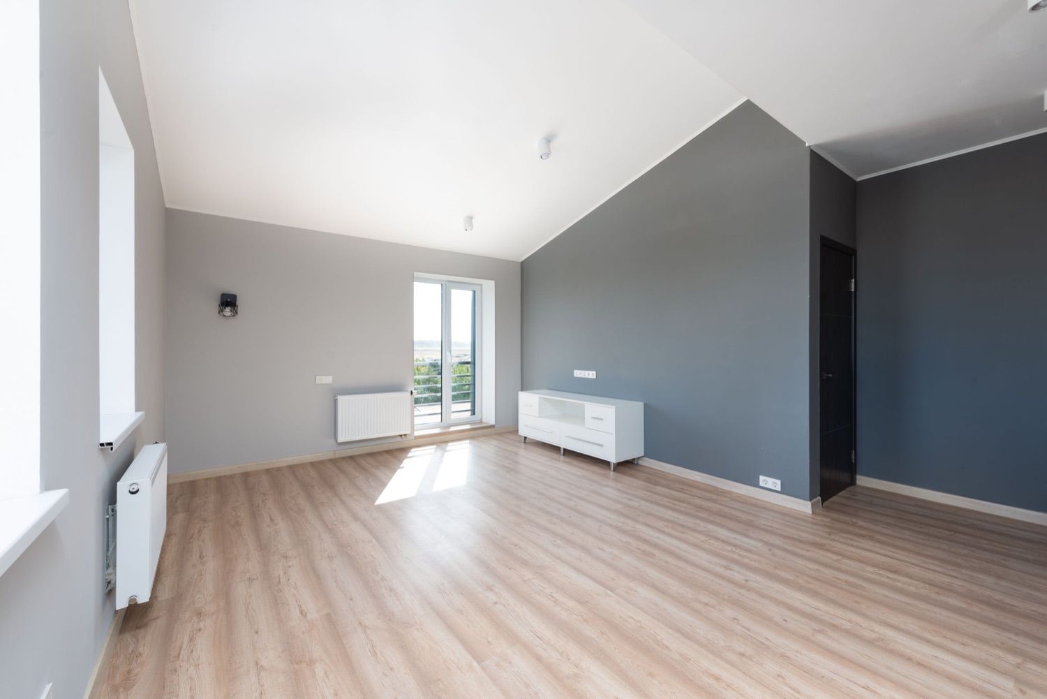 Cameră renovată cu parchet laminat, calorifere noi și ușă de balcon termopan albă
