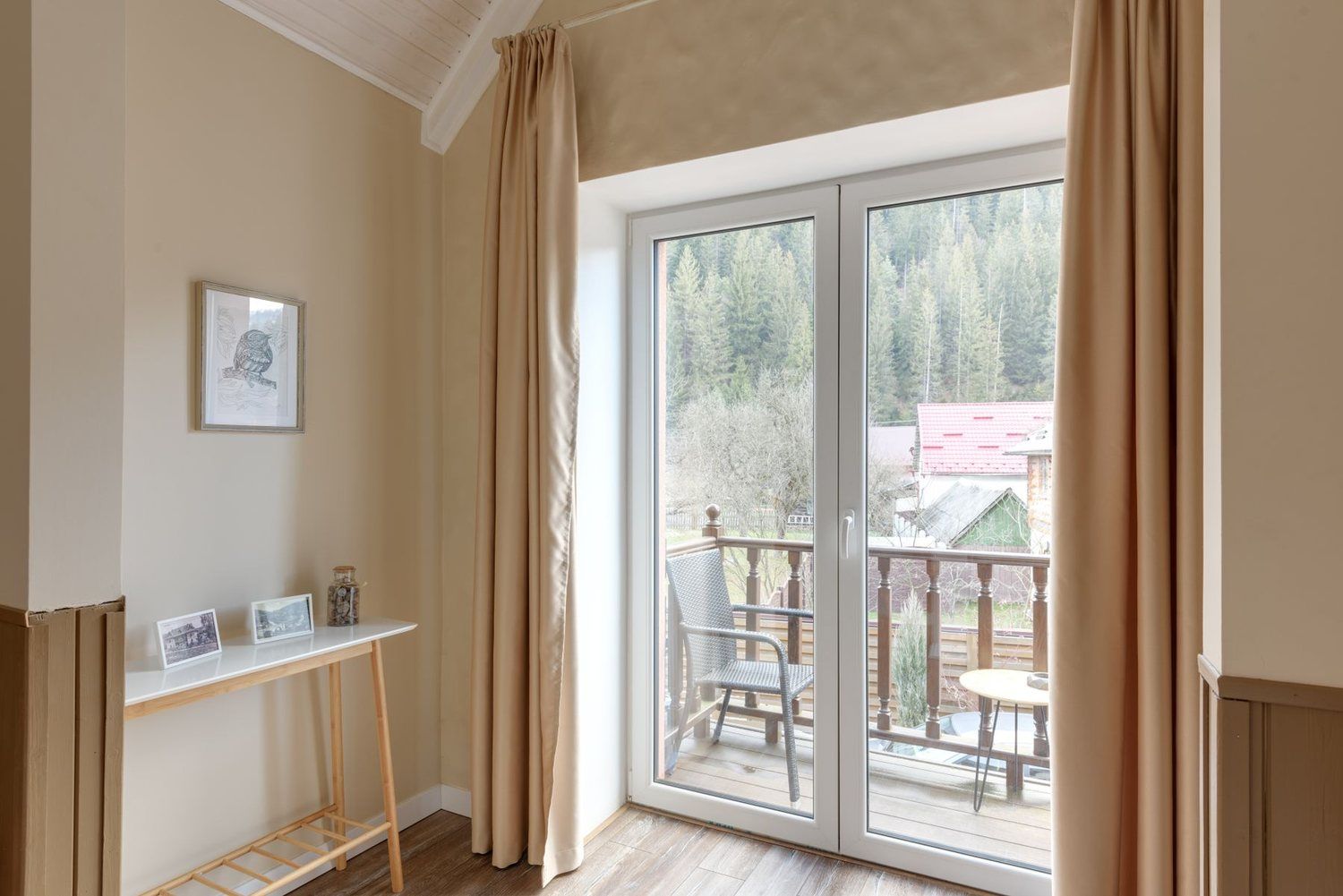 Ușă de balcon albă cu două canate vitrate, spre un balcon cu masă și vedere spre pădure