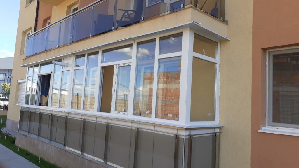 Balcon de la parterul unui bloc nou, închis cu tâmplărie PVC albă