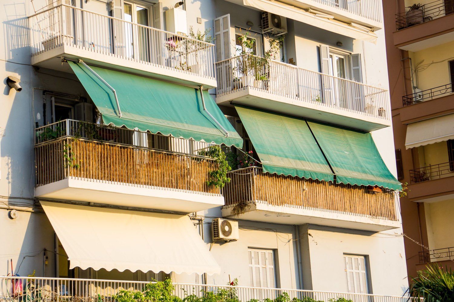 Balcoane de bloc cu copertine retractabile cu braț, cu pânză verde și crem
